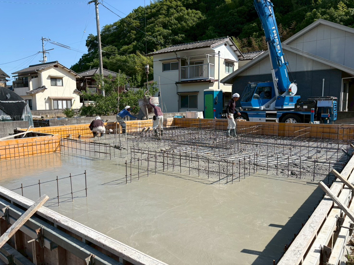 宇和島市の新築施工現場にて、耐震等級3の強固な基礎を形成するためにベースコンクリートを流し込む打設作業の様子