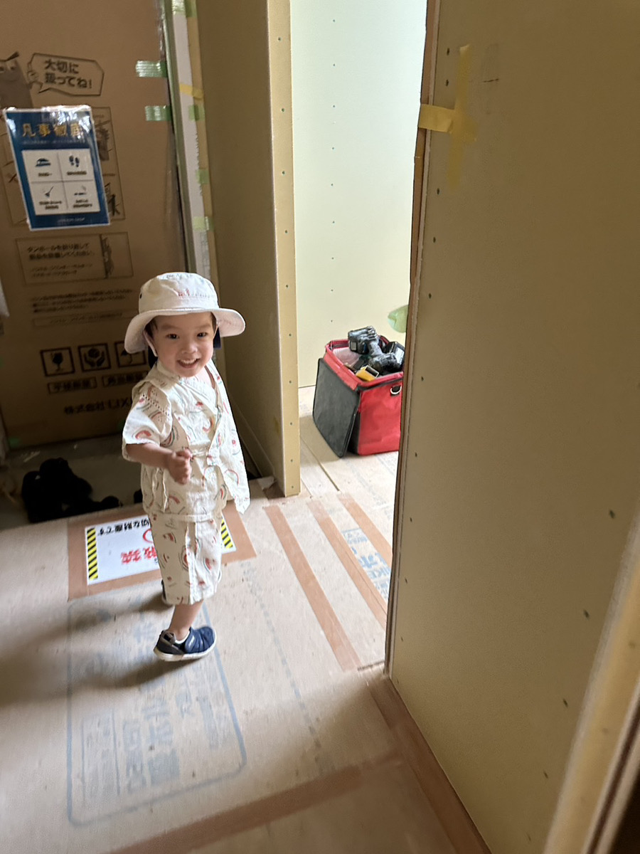 探検家のようなハットをかぶった男の子が、施工中の真新しい家の廊下を元気に歩く様子