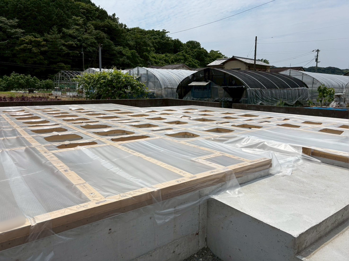 組み上がった土台全体に透明な養生シートを被せ、雨や汚れから保護している現場の様子