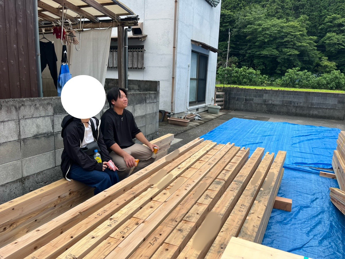 建築現場の資材の前で、進捗を笑顔で見守るO様ご夫婦