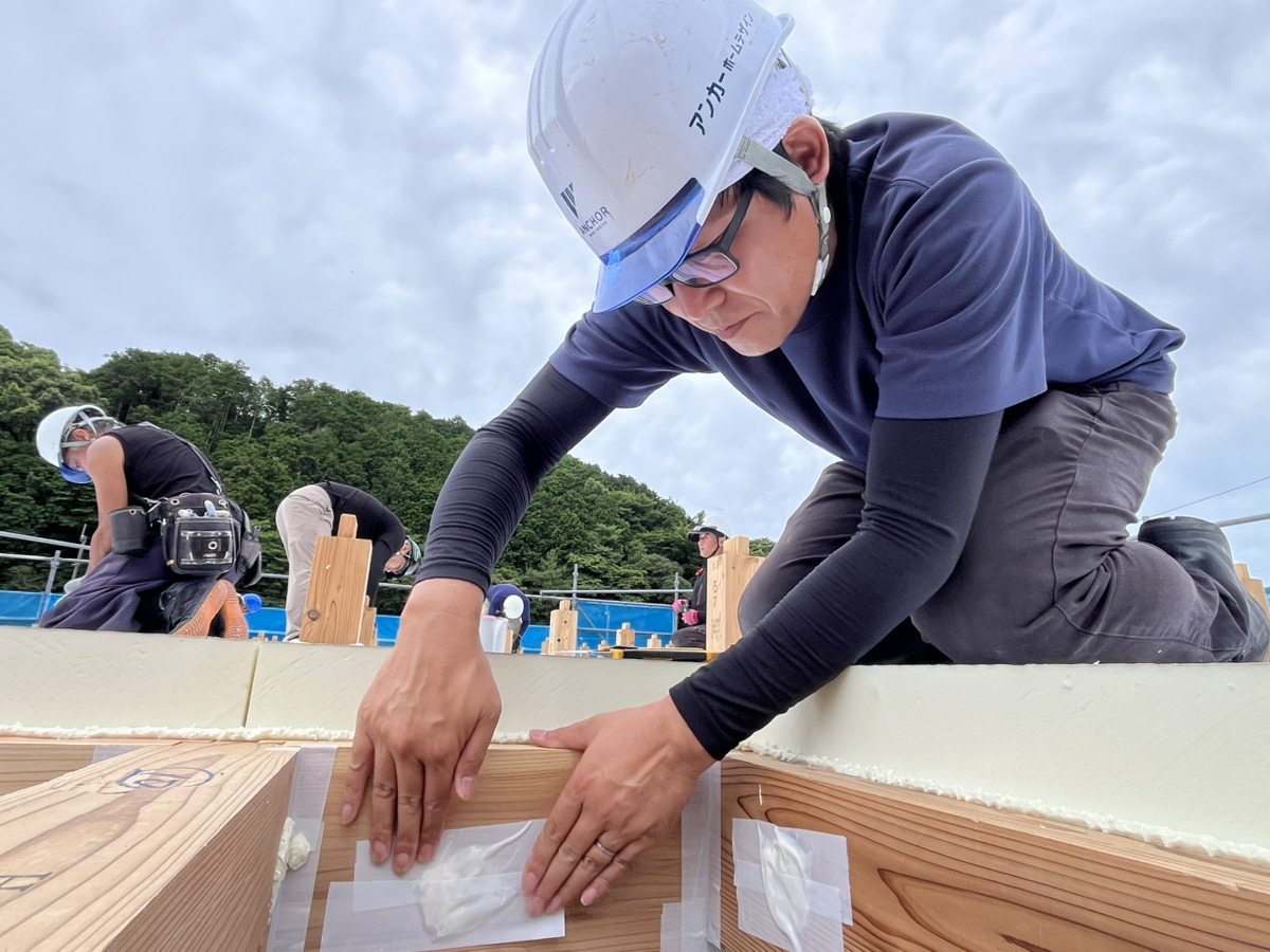 スタッフが柱の接合部に気密テープを丁寧に貼っている様子