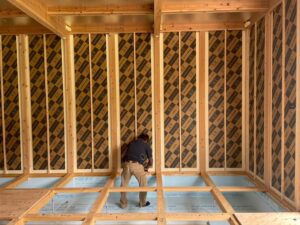 建物内部から見た壁・床・天井全面にLIXIL SWパネルが施工された状態。作業員が床の気密処理を進めている。